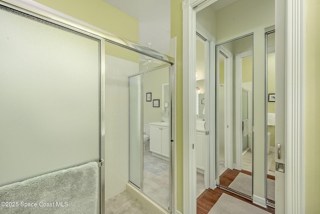 bathroom with wood finished floors and a stall shower