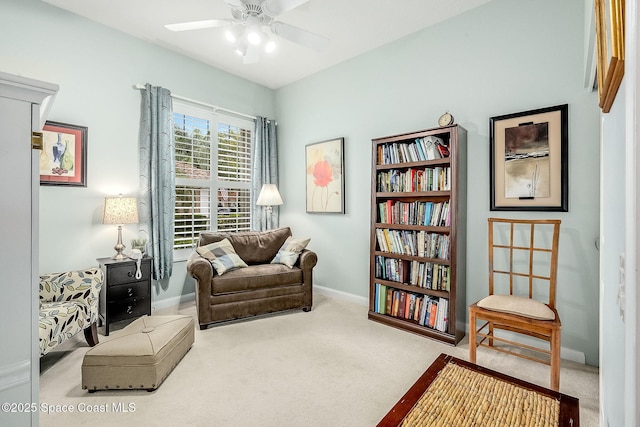 living area with baseboards, carpet, and a ceiling fan