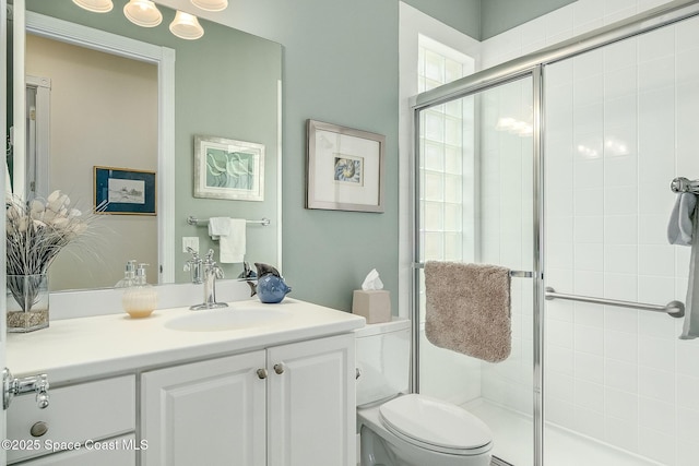 bathroom with a shower stall, vanity, and toilet