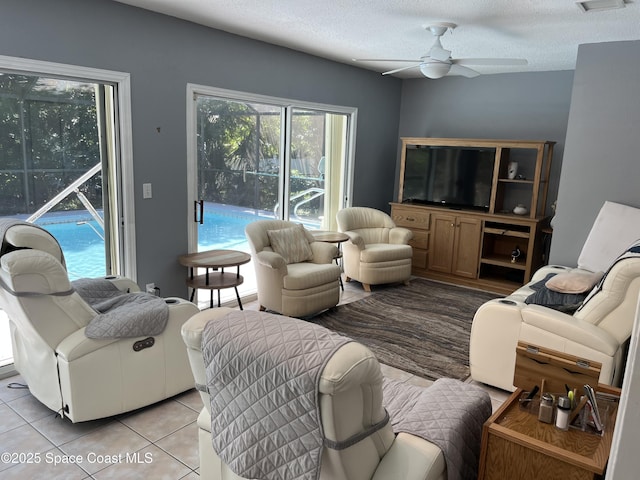 living area with visible vents, ceiling fan, a textured ceiling, and light tile patterned floors