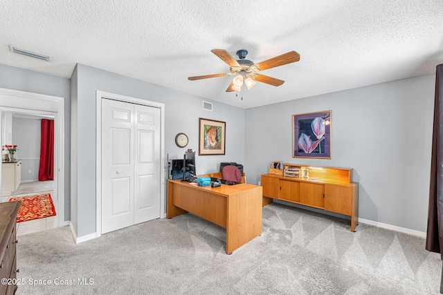 office area featuring a ceiling fan, visible vents, light carpet, and baseboards