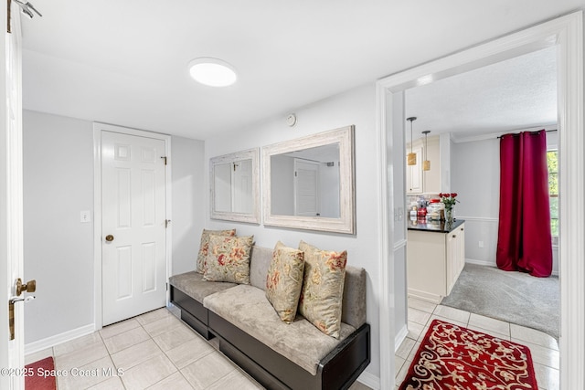 living room featuring baseboards, light colored carpet, and light tile patterned flooring