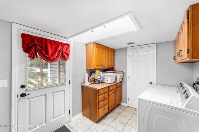 laundry area with cabinet space, visible vents, baseboards, washer and clothes dryer, and light tile patterned flooring