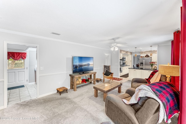 living room featuring crown molding, light colored carpet, visible vents, ceiling fan, and baseboards