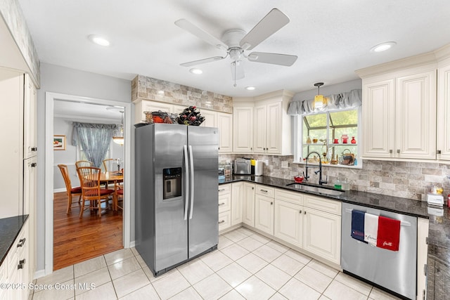 kitchen featuring stainless steel appliances, tasteful backsplash, a sink, and light tile patterned floors