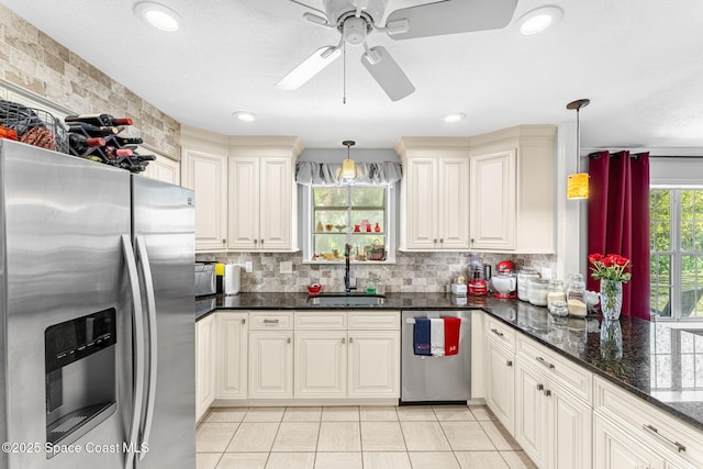 kitchen with decorative light fixtures, light tile patterned floors, backsplash, appliances with stainless steel finishes, and a sink