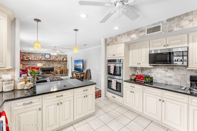 kitchen featuring stainless steel appliances, visible vents, backsplash, a brick fireplace, and open floor plan