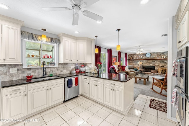 kitchen with open floor plan, a peninsula, stainless steel appliances, a sink, and light tile patterned flooring