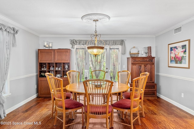 dining area with baseboards, visible vents, wood finished floors, and ornamental molding