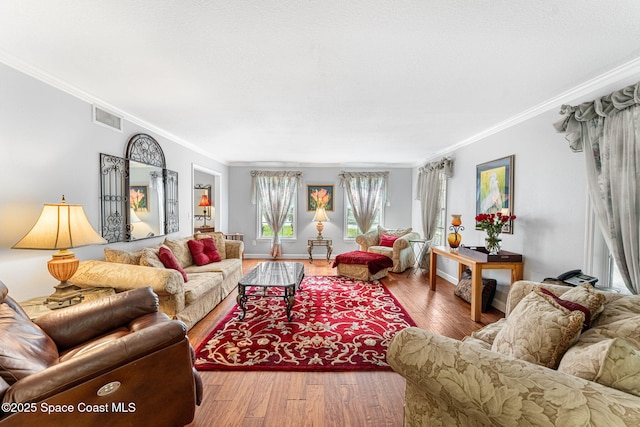 living room with ornamental molding, wood finished floors, visible vents, and baseboards