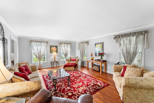 living area with ornamental molding, a textured ceiling, baseboards, and wood finished floors