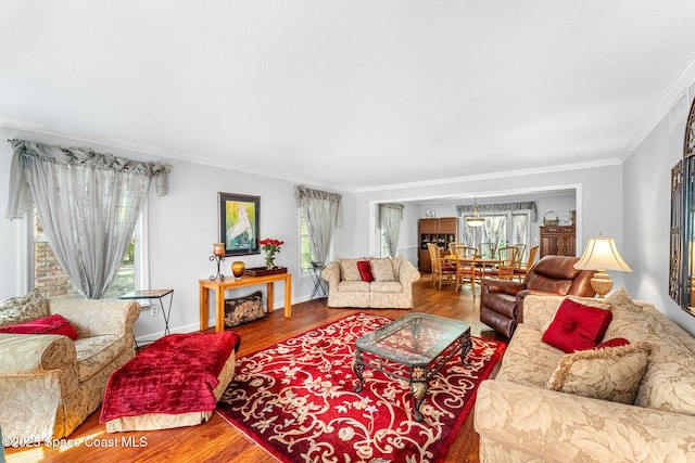 living room with crown molding, baseboards, and wood finished floors