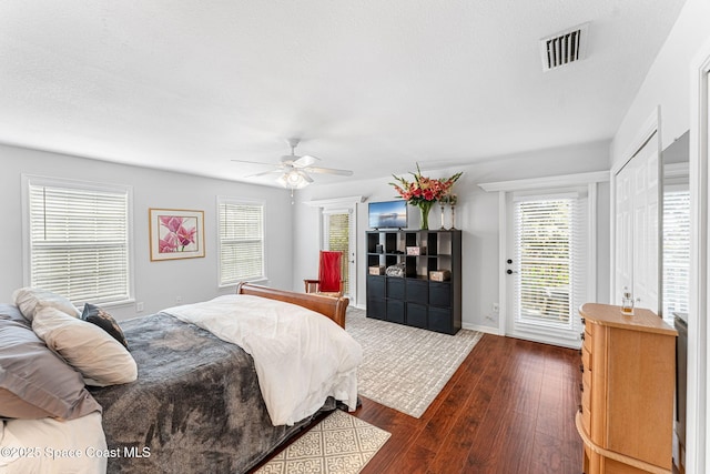 bedroom featuring access to exterior, multiple windows, visible vents, and dark wood finished floors