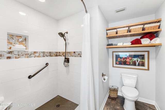 bathroom featuring baseboards, visible vents, a tile shower, and toilet