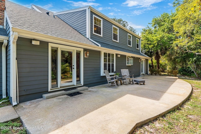 rear view of property with a shingled roof and a patio area