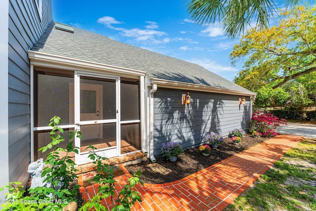 view of side of home with a shingled roof and a sunroom