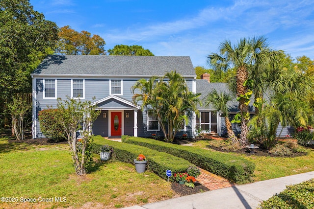 view of front facade with roof with shingles and a front yard