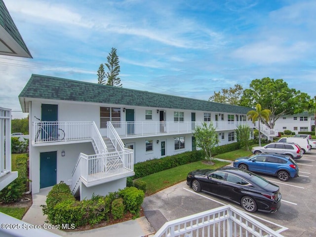 view of property with uncovered parking and stairway