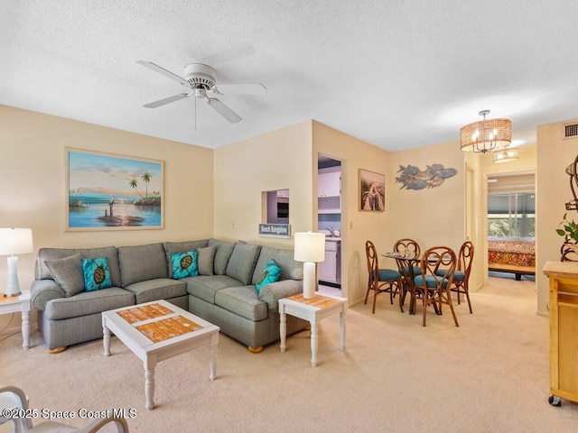 living area featuring a textured ceiling, visible vents, ceiling fan with notable chandelier, and light carpet