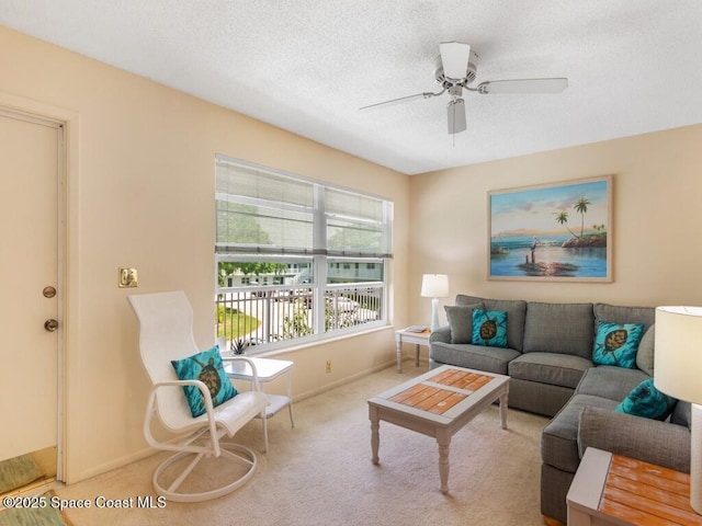 carpeted living room with ceiling fan, a textured ceiling, and baseboards