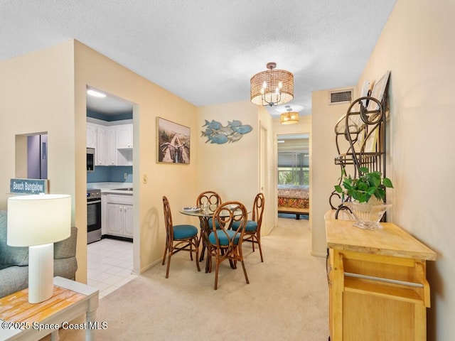 dining room featuring light carpet, baseboards, visible vents, a textured ceiling, and a notable chandelier