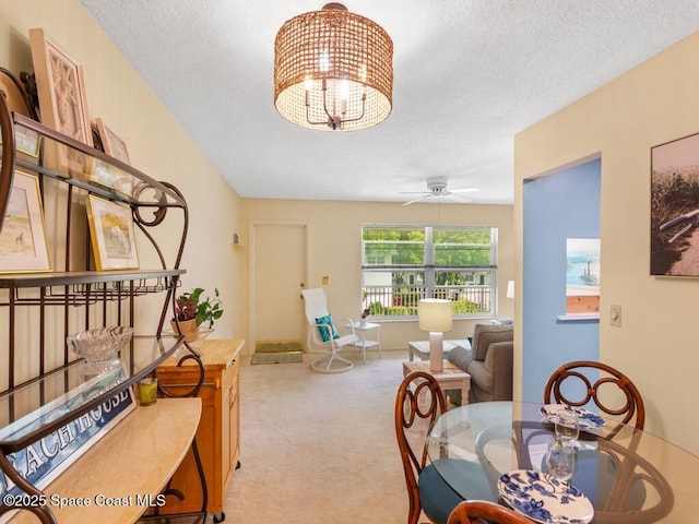 dining room with a textured ceiling, carpet flooring, and ceiling fan with notable chandelier