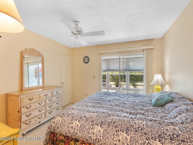 bedroom with a textured ceiling, access to outside, ceiling fan, and light colored carpet