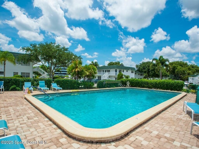 community pool with a patio and fence