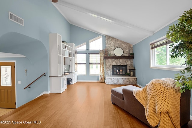 living area with vaulted ceiling with beams, a fireplace, visible vents, wood finished floors, and baseboards