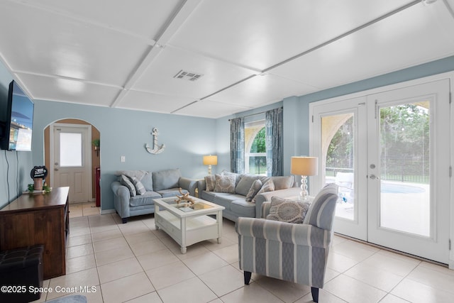 living area featuring arched walkways, french doors, visible vents, and light tile patterned floors