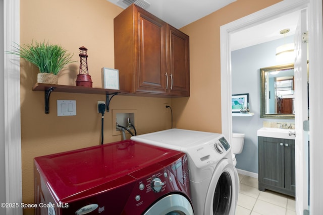 laundry area with light tile patterned floors, visible vents, cabinet space, washing machine and dryer, and a sink