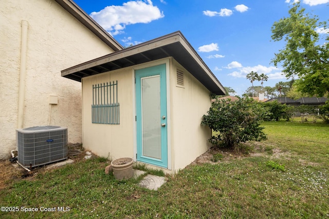 view of side of home with an outbuilding, stucco siding, a yard, and central air condition unit