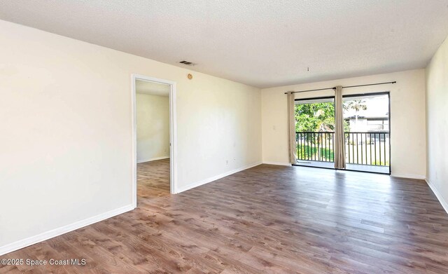 spare room with baseboards, a textured ceiling, visible vents, and wood finished floors