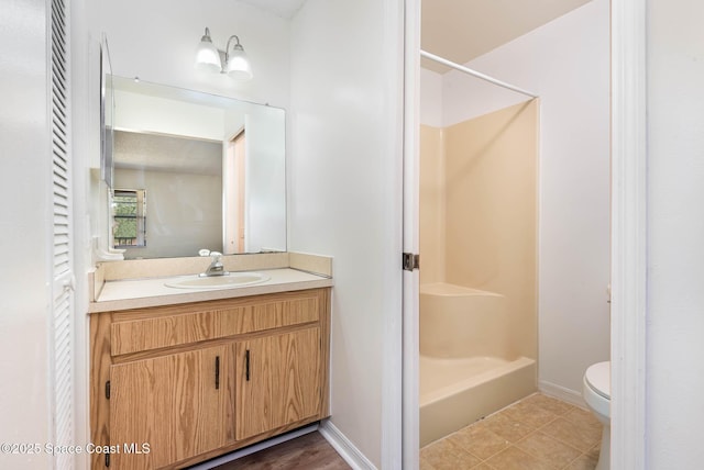 bathroom with toilet, vanity, tile patterned flooring, baseboards, and walk in shower