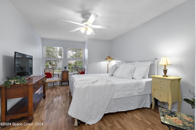 bedroom featuring a textured ceiling, a ceiling fan, and wood finished floors