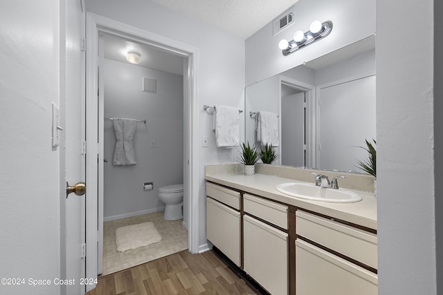 bathroom with toilet, visible vents, wood finished floors, and vanity