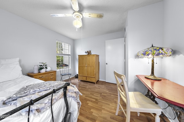 bedroom with ceiling fan, a textured ceiling, and light wood finished floors