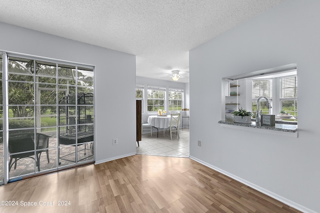 unfurnished room featuring a textured ceiling, wood finished floors, a ceiling fan, and baseboards