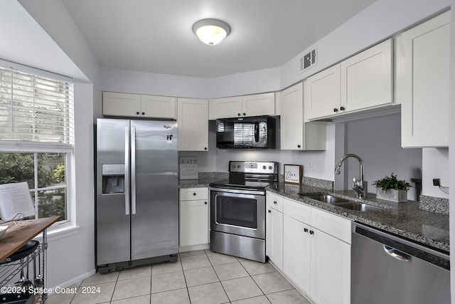 kitchen featuring stainless steel appliances, a sink, visible vents, dark stone counters, and plenty of natural light