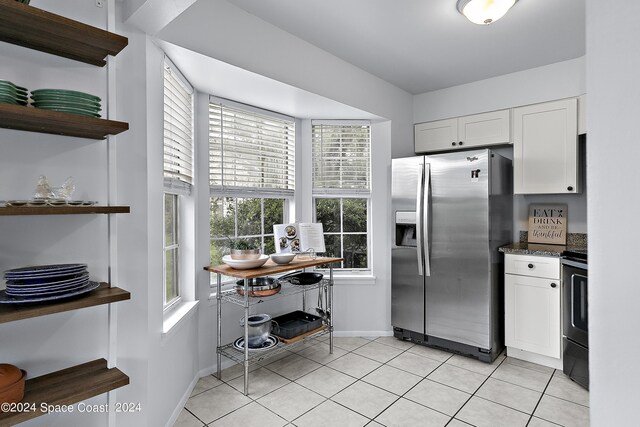 kitchen with electric range oven, light tile patterned floors, white cabinets, and stainless steel fridge with ice dispenser