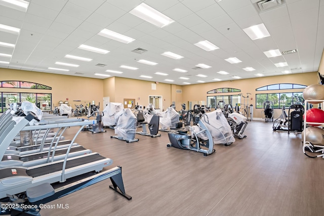 exercise room with a paneled ceiling, wood finished floors, and visible vents