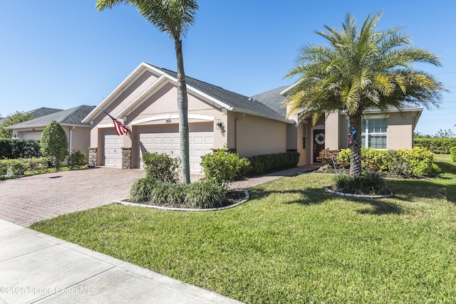 view of front of property with a garage, decorative driveway, a front yard, and stucco siding