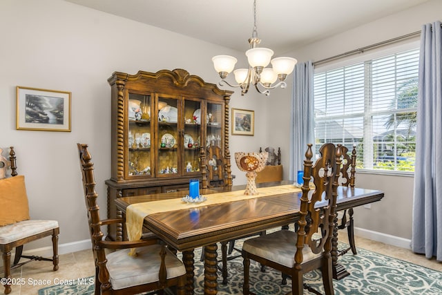 dining area with baseboards, a notable chandelier, and light tile patterned flooring