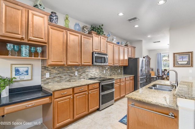 kitchen with appliances with stainless steel finishes, a sink, visible vents, and tasteful backsplash