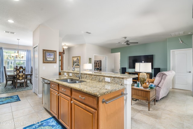 kitchen with brown cabinets, visible vents, a sink, and an island with sink