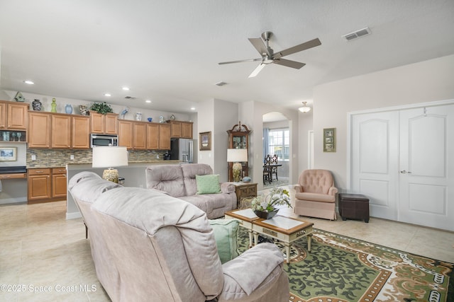 living room with light tile patterned floors, visible vents, arched walkways, ceiling fan, and recessed lighting