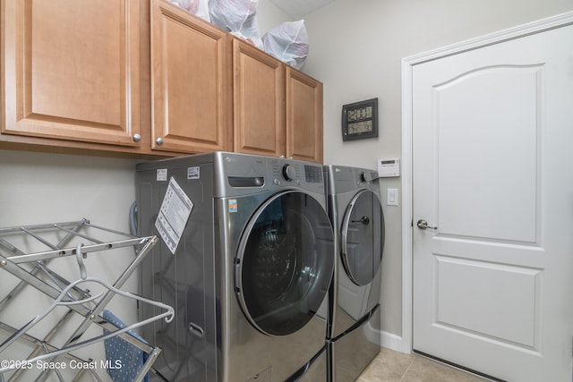 laundry area with cabinet space, light tile patterned floors, and independent washer and dryer