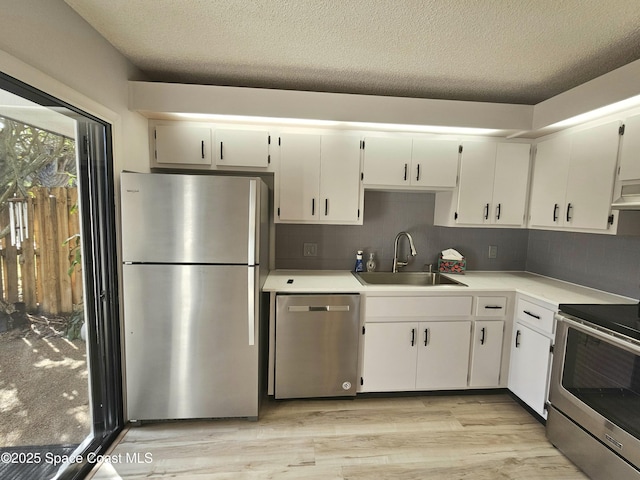 kitchen featuring stainless steel appliances, tasteful backsplash, light countertops, light wood-style flooring, and a sink