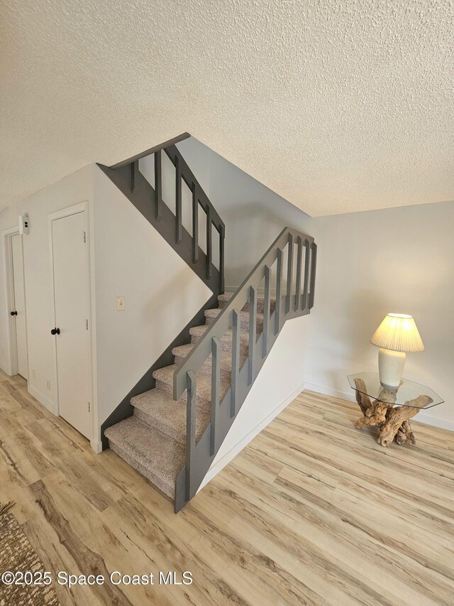 stairway featuring a textured ceiling and wood finished floors