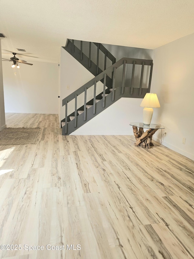 interior space featuring visible vents, a ceiling fan, a textured ceiling, wood finished floors, and stairs